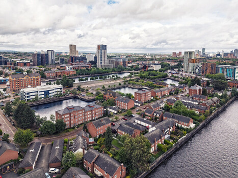 Aerial view of MediaCityUK featuring modern office buildings residential brick houses and waterfront docks under a cloudy sky in Salford England United Kingdom. Aerial view of MediaCityUK featuring modern office buildings residential brick houses and waterfront docks under a cloudy sky in Salford England United Kingdom.