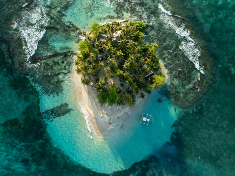 Aerial view of Guyam Island with dense palm trees white sand beach and turquoise water surrounded by coral reefs in General Luna Caraga Philippines. Aerial view of Guyam Island with dense palm trees white sand beach and turquoise water surrounded by coral reefs in General Luna Caraga Philippines.