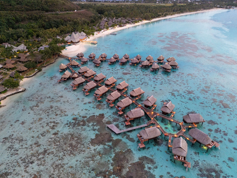 Aerial view of Sofitel Kia Ora Moorea Beach Resort with overwater bungalows in the turquoise lagoon surrounded by coral reefs and lush coastline. Moorea Maiao Windward Islands French Polynesia. Aerial view of Sofitel Kia Ora Moorea Beach Resort with overwater bungalows in the turquoise lagoon surrounded by coral reefs and lush coastline. Moorea Maiao Windward Islands French Polynesia.