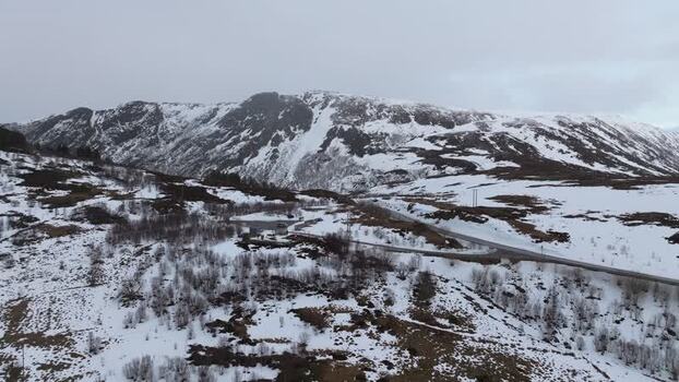 Aerial view of snowy mountains and a winding road in Lofoten Norway.