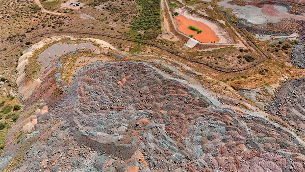 Aerial view of a striking industrial landscape where layered earth in hues of rust and grey meets a vivid orange reservoir Rustenburg North West South Africa. Aerial view of a striking industrial landscape where layered earth in hues of rust and grey meets a vivid orange reservoir Rustenburg North West South Africa.