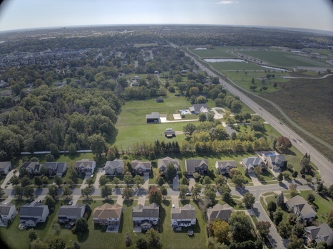 Aerial view of a suburban residential neighborhood with single family homes green lawns tree lined streets and autumn foliage in Mason Ohio United States.