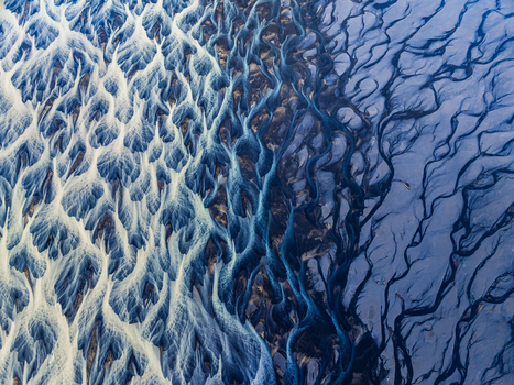 Aerial view of the intricate braided river system with dark volcanic sediment and glacial meltwater flowing through the landscape of Iceland. Aerial view of the intricate braided river system with dark volcanic sediment and glacial meltwater flowing through the landscape of Iceland.
