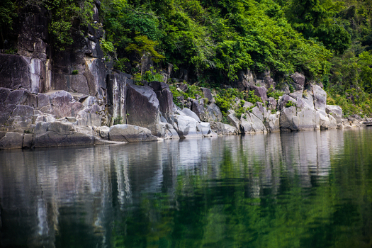 Meghalaya India 31 March 2023 View of the crystal clear river flowing past steep rocky cliffs covered in lush green vegetation. Meghalaya India 31 March 2023 View of the crystal clear river flowing past steep rocky cliffs covered in lush green vegetation.