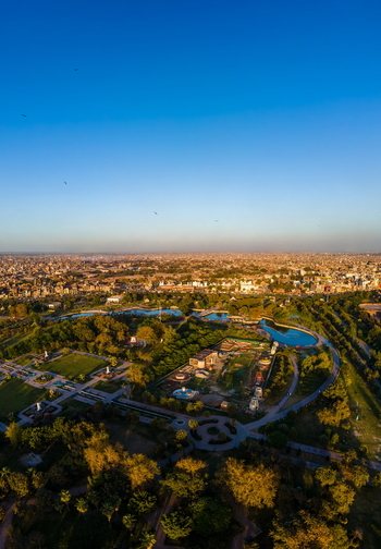 Aerial view of Minar e Pakistan in Iqbal Park with water features and the urban skyline of Lahore in the background at sunset Lahore Punjab Pakistan.
