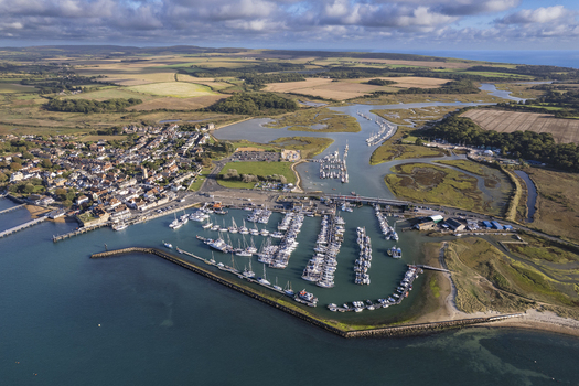 Aerial view of Yarmouth harbour with its marina filled with boats surrounded by the historic town green fields and coastal landscape on the Isle of Wight United Kingdom. Aerial view of Yarmouth harbour with its marina filled with boats surrounded by the historic town green fields and coastal landscape on the Isle of Wight United Kingdom.