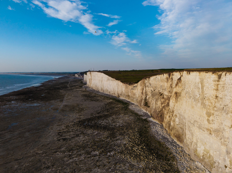Aerial view of Beach of the Bois de Cise with dramatic white chalk cliffs rocky shoreline and calm sea under a clear blue sky Ault Hauts de France France.