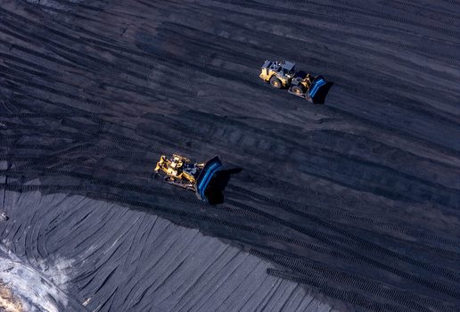 Aerial view of heavy machinery operating on a large coal pile at a power plant in West Olive Michigan United States. Aerial view of heavy machinery operating on a large coal pile at a power plant in West Olive Michigan United States.