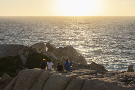 View of people sitting on granite rocks watching the sunset over the Mediterranean Sea at Capo Testa Sardegna Italy. View of people sitting on granite rocks watching the sunset over the Mediterranean Sea at Capo Testa Sardegna Italy.