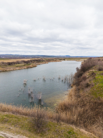 Aerial view of Lake Atanasovsko with dry reeds on the banks and rolling hills under a cloudy sky Burgas Burgas Bulgaria. Aerial view of Lake Atanasovsko with dry reeds on the banks and rolling hills under a cloudy sky Burgas Burgas Bulgaria.