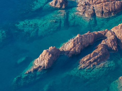 Aerial view of the rugged red rock formations of Le Trayas emerging from the clear turquoise waters of the Mediterranean Sea in Saint Raphael Provence Alpes Cote d Azur France. Aerial view of the rugged red rock formations of Le Trayas emerging from the clear turquoise waters of the Mediterranean Sea in Saint Raphael Provence Alpes Cote d Azur France.