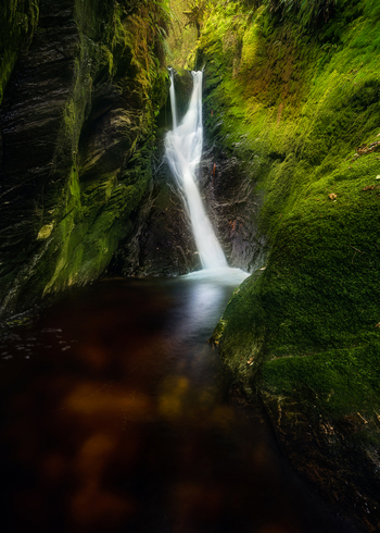 View of a waterfall cascading down a moss covered rocky gorge along the Wicklow Way in County Wicklow Ireland. View of a waterfall cascading down a moss covered rocky gorge along the Wicklow Way in County Wicklow Ireland.