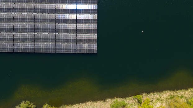 Aerial view of floating solar panels on a dark lake with green shoreline vegetation in Zwolle Overijssel Netherlands. Aerial view of floating solar panels on a dark lake with green shoreline vegetation in Zwolle Overijssel Netherlands.