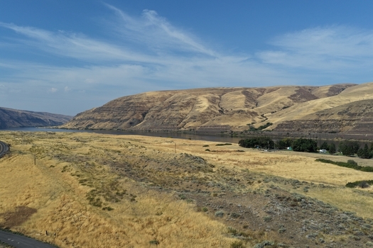 Aerial view of the Snake River winding through golden rolling hills dry grassy plains and scattered trees under a clear blue sky in Whitman County Washington United States. Aerial view of the Snake River winding through golden rolling hills dry grassy plains and scattered trees under a clear blue sky in Whitman County Washington United States.