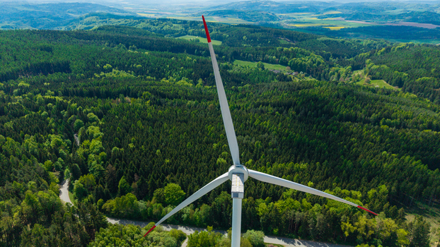 Aerial view of a wind turbine at Zipotin with red tipped blades surrounded by dense green forest and rolling hills in Gruna Pardubicky kraj Czechia. Aerial view of a wind turbine at Zipotin with red tipped blades surrounded by dense green forest and rolling hills in Gruna Pardubicky kraj Czechia.