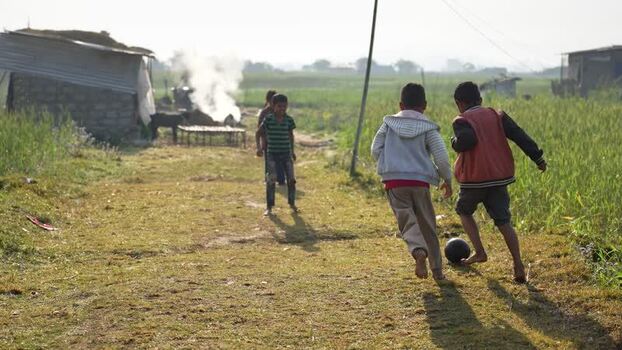 View of children playing football in a rural field Nepal.