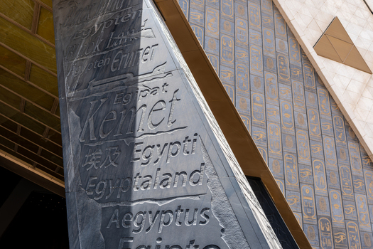 Giza Egypt 16 May 2026 View of the Grand Egyptian Museum facade with a stone pillar engraved with the name of the country in various languages and golden hieroglyphs.