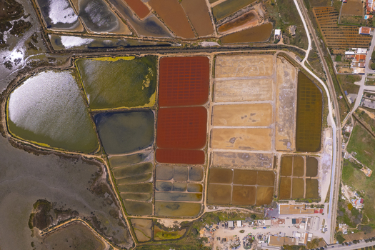 Aerial view of Salinas do Grelha salt pans featuring vibrant red green and brown evaporation ponds arranged in geometric patterns Olhao Faro Portugal. Aerial view of Salinas do Grelha salt pans featuring vibrant red green and brown evaporation ponds arranged in geometric patterns Olhao Faro Portugal.