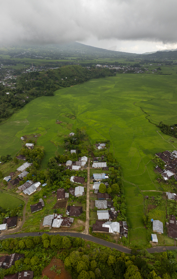 Aerial view of Lingko Spider Web Rice Fields surrounded by lush green paddies and a small village in Ruteng East Nusa Tenggara Indonesia.