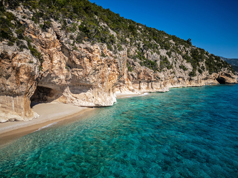 Aerial view of the limestone cliffs and sea caves of Cala Luna beach with turquoise water and lush vegetation in Baunei Sardegna Italy. Aerial view of the limestone cliffs and sea caves of Cala Luna beach with turquoise water and lush vegetation in Baunei Sardegna Italy.
