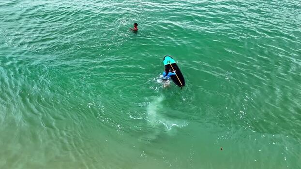 Aerial view of surfer in turquoise ocean waters in Bali Indonesia.