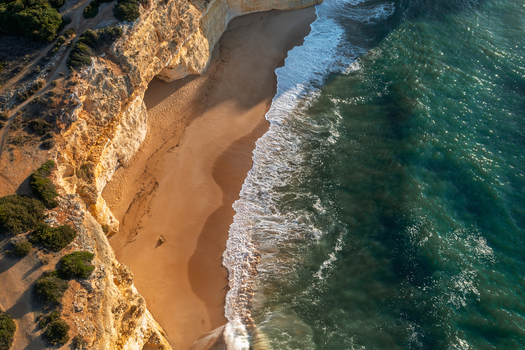 Aerial view of Caramujeira beach with golden sand dramatic limestone cliffs and turquoise Atlantic ocean waves in Lagoa Faro Portugal. Aerial view of Caramujeira beach with golden sand dramatic limestone cliffs and turquoise Atlantic ocean waves in Lagoa Faro Portugal.