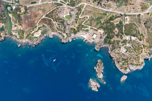 Aerial view of Riserva Naturale Orientata dello Zingaro with rugged rocky coastline turquoise waters and a small boat anchored near the shore in San Vito Lo Capo Sicilia Italy. Aerial view of Riserva Naturale Orientata dello Zingaro with rugged rocky coastline turquoise waters and a small boat anchored near the shore in San Vito Lo Capo Sicilia Italy.