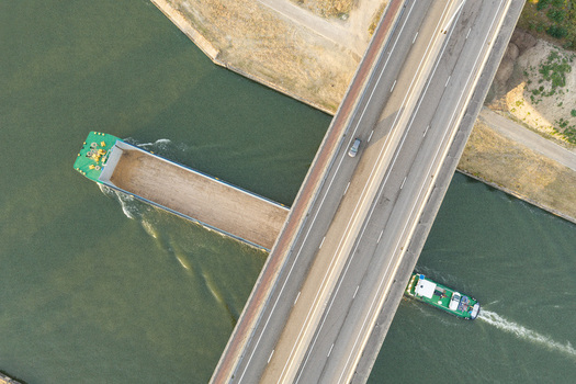 Aerial view of a cargo barge navigating the canal under a bridge at Haven Genk Genk Vlaanderen Belgium.