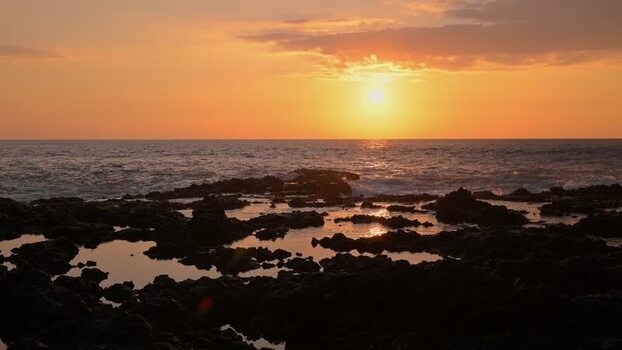 View of waves crashing on a rocky coast at sunset United States.