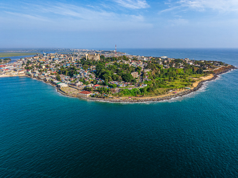 Aerial view of the coastal city featuring dense urban buildings lush green vegetation and a rocky coastline along the blue Atlantic Ocean Monrovia Montserrado Liberia. Aerial view of the coastal city featuring dense urban buildings lush green vegetation and a rocky coastline along the blue Atlantic Ocean Monrovia Montserrado Liberia.