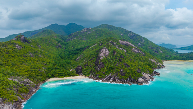 Aerial view of the lush green hills and granite rock formations of Cap Ternay meeting the turquoise waters of the Indian Ocean in Cap Ternay Port Glaud Seychelles. Aerial view of the lush green hills and granite rock formations of Cap Ternay meeting the turquoise waters of the Indian Ocean in Cap Ternay Port Glaud Seychelles.