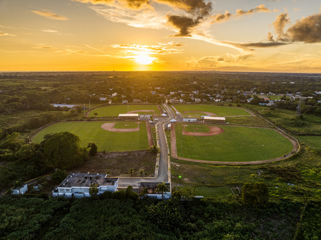 Aerial view of Quality Baseball Academy featuring multiple baseball fields lush green surroundings and a sunset sky in San Antonio de Guerra Santo Domingo Provinc Dominican Republic. Aerial view of Quality Baseball Academy featuring multiple baseball fields lush green surroundings and a sunset sky in San Antonio de Guerra Santo Domingo Provinc Dominican Republic.