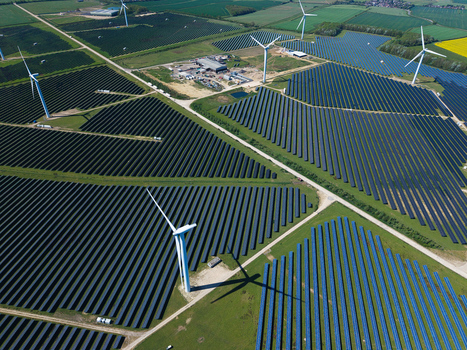 Aerial view of Chelveston Wind Farm featuring rows of solar panels and tall wind turbines across green fields in Wellingborough England United Kingdom. Aerial view of Chelveston Wind Farm featuring rows of solar panels and tall wind turbines across green fields in Wellingborough England United Kingdom.