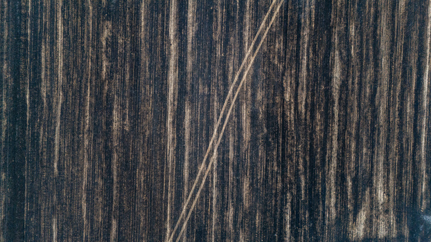 Aerial view of a freshly plowed agricultural field with distinct soil textures and parallel tractor tracks in Sremska Mitrovica Vojvodina Serbia.