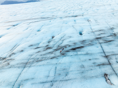 Aerial view of Breidamerkurjokull glacier with hikers walking across the blue ice and crevasses in Sveitarfelagid Hornafjordur Iceland. Aerial view of Breidamerkurjokull glacier with hikers walking across the blue ice and crevasses in Sveitarfelagid Hornafjordur Iceland.