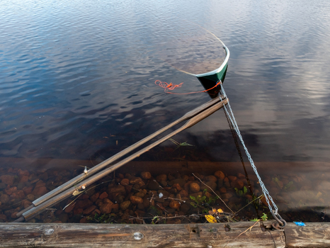 View of a row boat partially submerged in a river after a flood with wooden oars resting on the water surface near a wooden dock in Muhos North Ostrobothnia Finland.