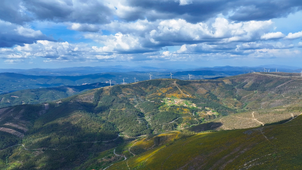 Aerial view of wind turbines on a green hilly landscape with scattered buildings under a cloudy sky in Lisbon Lisbon Portugal. Aerial view of wind turbines on a green hilly landscape with scattered buildings under a cloudy sky in Lisbon Lisbon Portugal.