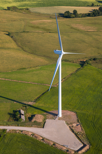 Aerial view of a solitary wind turbine stands tall against a patchwork of golden and green fields a symbol of renewable energy Salles Curan Occitanie France. Aerial view of a solitary wind turbine stands tall against a patchwork of golden and green fields a symbol of renewable energy Salles Curan Occitanie France.