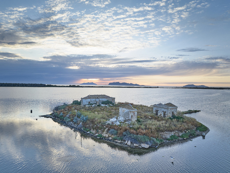 Aerial view of the historic Saline dello Stagnone salt pans featuring abandoned stone buildings on a small island surrounded by calm water at sunset in Marsala Sicilia Italy. Aerial view of the historic Saline dello Stagnone salt pans featuring abandoned stone buildings on a small island surrounded by calm water at sunset in Marsala Sicilia Italy.