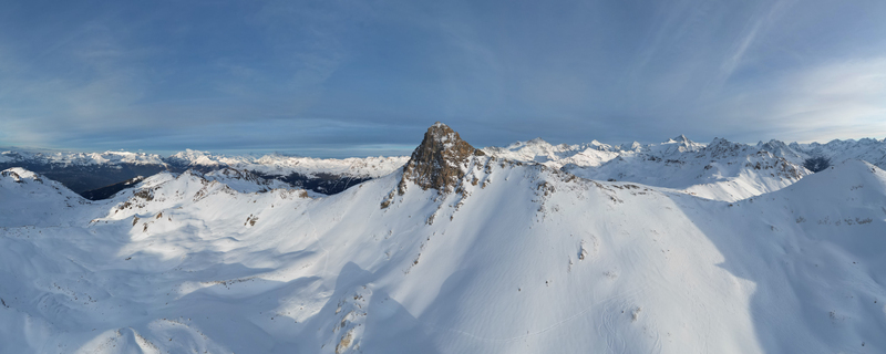 Aerial view of the snow blanketed rugged Becs des Bossons Peak piercing the sky surrounded by a sea of white peaks under a serene blue sky Anniviers Valais Switzerland.