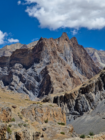 View of the rugged mountain landscape along the Penzi La road with dramatic rocky peaks steep slopes and a clear blue sky in Zanskar Ladakh India.