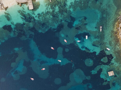Aerial view of small boats floating on the clear turquoise waters of the Ionian Sea near the coast of Ksamil Vlore County Albania. Aerial view of small boats floating on the clear turquoise waters of the Ionian Sea near the coast of Ksamil Vlore County Albania.