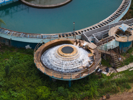 Aerial view of a circular water treatment clarifier with cascading water and industrial infrastructure surrounded by lush green vegetation in Karad Maharashtra India.