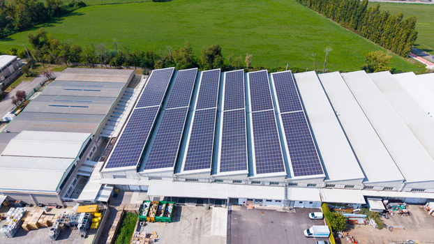 Aerial view of a large distribution center featuring extensive solar panel arrays on its roof surrounded by industrial infrastructure and green fields in Milan Lombardy Italy. Aerial view of a large distribution center featuring extensive solar panel arrays on its roof surrounded by industrial infrastructure and green fields in Milan Lombardy Italy.