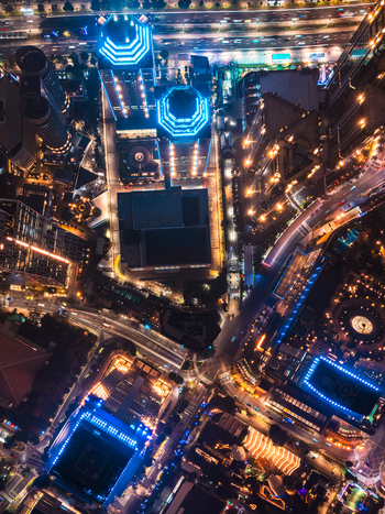 Aerial view of illuminated skyscrapers busy city streets with light trails from traffic and modern urban architecture in Jakarta Indonesia.