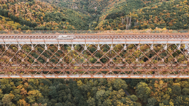 Aerial view of the historic Fades viaduct with its rusty metal truss structure spanning over a dense forest with autumn foliage in Les Ancizes Comps Auvergne Rhone Alpes France. Aerial view of the historic Fades viaduct with its rusty metal truss structure spanning over a dense forest with autumn foliage in Les Ancizes Comps Auvergne Rhone Alpes France.