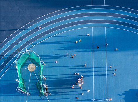 Aerial view of athletes training on a blue running track with a throwing cage in Santo Domingo Distrito Nacional Dominican Republic.