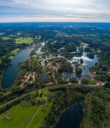 Aerial view of a vast landscape featuring interconnected lakes dense green forests winding dirt paths and open meadows Latvia. Aerial view of a vast landscape featuring interconnected lakes dense green forests winding dirt paths and open meadows Latvia.