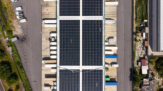 Aerial view of a logistics hub with a solar panel roof loading docks with parked semi trucks and industrial infrastructure in Melegnano Lombardy Italy.
