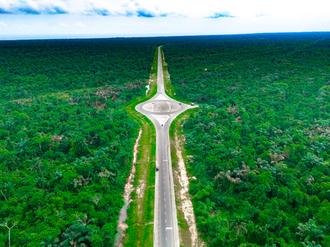 Aerial view of a modern road featuring a central roundabout cutting through the dense tropical forest of Bonny Island in Bonny Town Rivers Nigeria. Aerial view of a modern road featuring a central roundabout cutting through the dense tropical forest of Bonny Island in Bonny Town Rivers Nigeria.